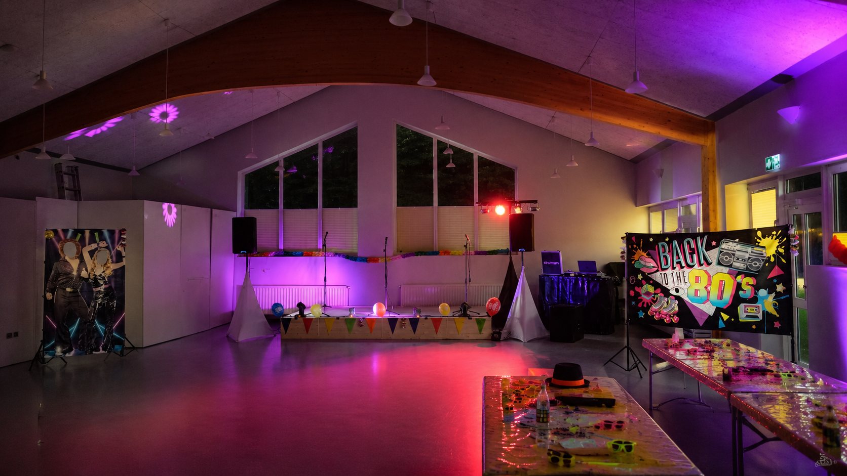 Vollständig aufgebaute 80er-Mottoparty-Location mit DJ-Equipment vor Gästeempfang